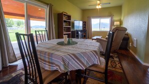 A dining area with a table set for four, a bookshelf, a television, and a chair. - The Cascade Mountain-View Retreat (Fort Klamath)