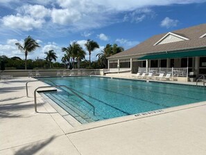 Relax by the pool surrounded by lounge chairs and umbrellas on a shaded patio.