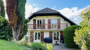 Ein zweistöckiges Haus mit Balkon, Grill und Terrassentisch.