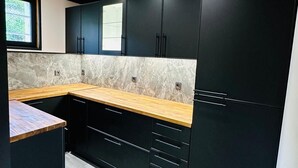 Eine moderne Küche mit schwarzen Schränken, einer Holzarbeitsplatte und einer Marmor-Spritzschutzwand.