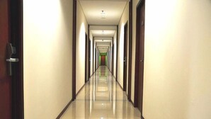 A long, narrow hotel corridor with doors on both sides and a shiny tiled floor. - Thamrin Condotel (Jakarta)