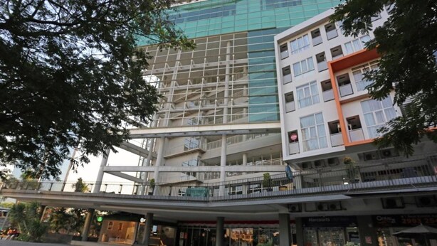 A multi-story building with a modern architectural design, featuring a glass facade and a covered pedestrian walkway. - Thamrin Condotel (Jakarta)