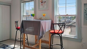 Ein Essbereich mit Tisch und zwei Stühlen, einem Fenster mit Blick und einem gerahmten Kunstwerk an der Wand.