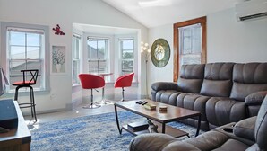 Ein Wohnzimmer mit einer Ledersofa, zwei roten Sesseln, einem Couchtisch und einem blau gemusterten Teppich.