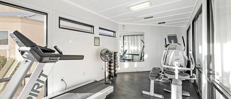 A gym with a treadmill, elliptical, and weight machine.