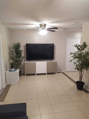 Relax in this cozy space with a flat-screen TV, ceiling fan, and comfortable sofa.