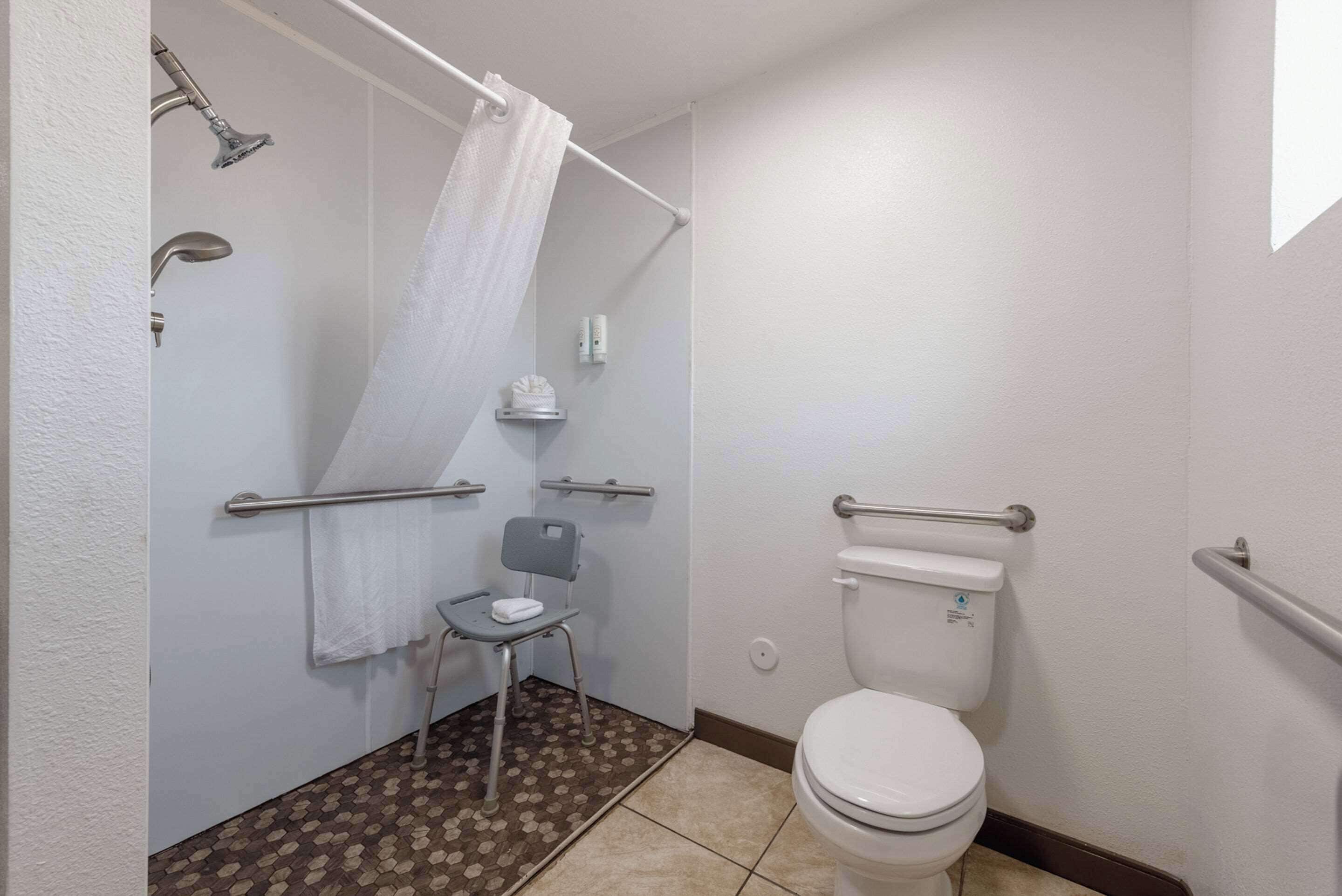 Un baño con ducha, inodoro y una silla.