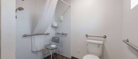 Un baño con ducha, inodoro y una silla.