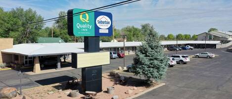 A Suburban Inn by Quality Inn & Suites with a parking lot and a building with a green roof.