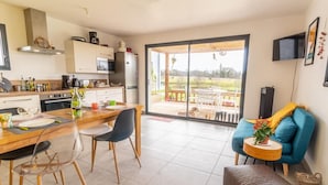 A modern kitchen with a dining area, a large sliding glass door to an outdoor patio, and a cozy seating area with a blue sofa and a small table.