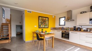A bright yellow kitchen with a dining area, wooden furniture, and a modern stove.