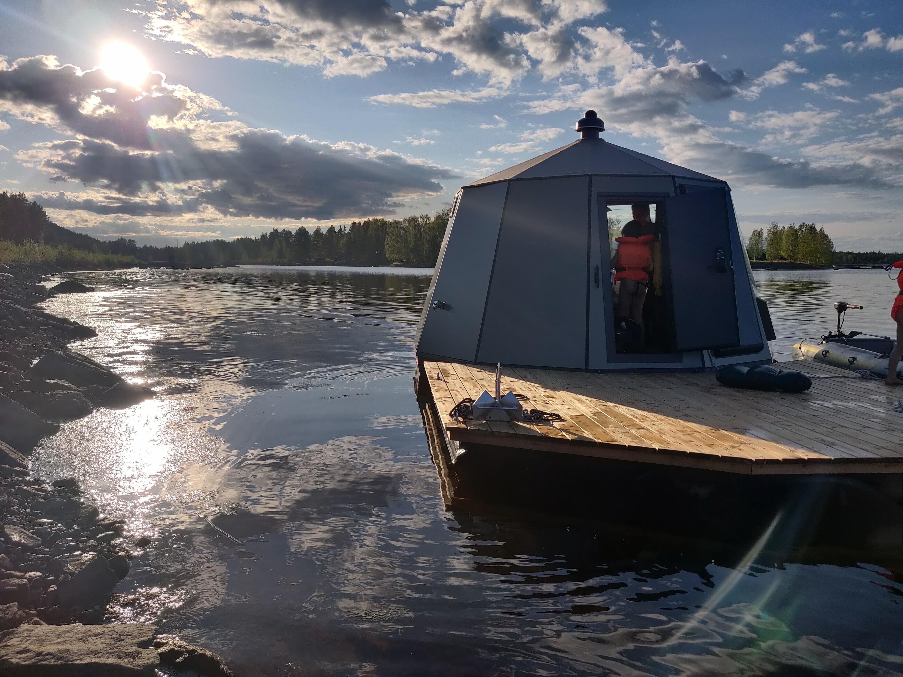 A tent on a wooden dock by a calm lake with a clear sky.