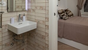 Une salle de bain équipée d’un lavabo, d’un miroir et d’un distributeur de serviettes.