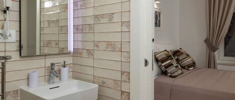 A bathroom with a sink, mirror, and towel dispenser.