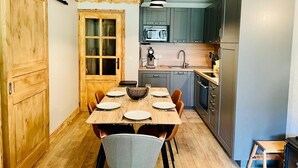 Una cocina compacta con una mesa de comedor de madera dispuesta para cuatro personas, un microondas y un refrigerador.