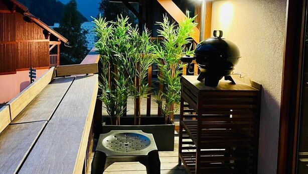 Terraza de madera con una parrilla y mobiliario para exteriores.