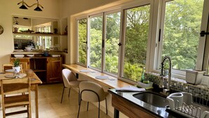 Une cuisine dotée d’une grande fenêtre, de meubles en bois et d’un coin repas avec des chaises.