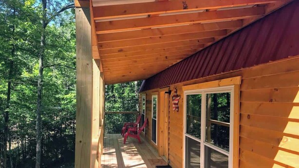 A wooden cabin with a covered porch, large windows, and a view of a forested area. - Cozy Wooded Cabin in the Heart of RRG! (Campton)