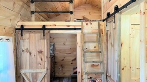 A wooden interior with a loft area, a ladder, and a welcome sign. - Cozy Wooded Cabin in the Heart of RRG! (Campton)