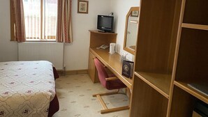 A hotel room with a bed, a desk with a television, a chair, a wardrobe, and a window with curtains. - Bessemer Hotel (Merthyr Tydfil)