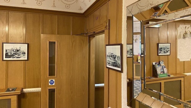 A hotel room with wooden paneling, a large mirror, and framed black and white photographs on the walls. - Bessemer Hotel (Merthyr Tydfil)