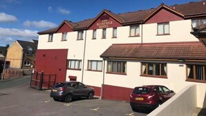 A hotel with a red and white facade, multiple windows, and a parking area with cars. - Bessemer Hotel (Merthyr Tydfil)