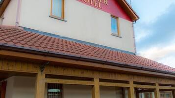 A two-story building with a red and white facade, labeled "The Bessmer Hotel." It features a tiled roof, wooden balcony railings, and multiple windows.