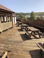 A wooden deck with picnic tables and a building with windows.