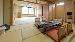 A traditional Japanese room with tatami flooring, a low table with tea sets, and sliding doors. - Hotel Koryu (Fujikawaguchiko)