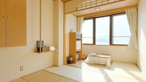 A traditional Japanese room with tatami flooring, a low table with tea set, and a view of the sea through large windows. - Hotel Koryu (Fujikawaguchiko)