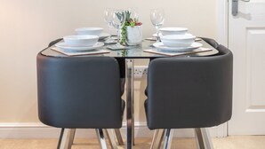 A dining area with a table set for two, featuring black chairs and a glass table. - Apartment 5 (Worksop)
