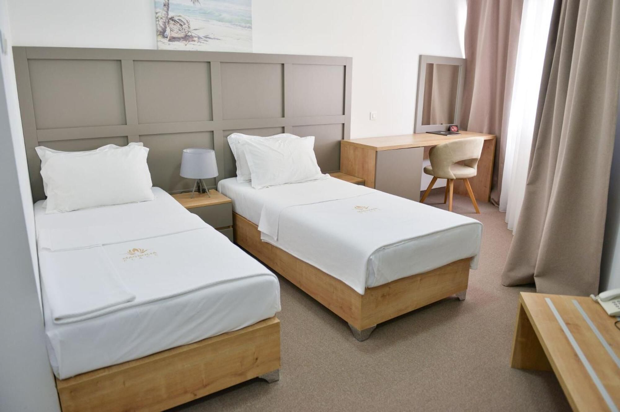 Habitación de hotel con dos camas, un escritorio, una silla y una mesita.