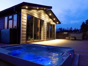 A wooden cabin with a hot tub and deck furniture. - Hollicarrs - Dragonfly Lodge (York)