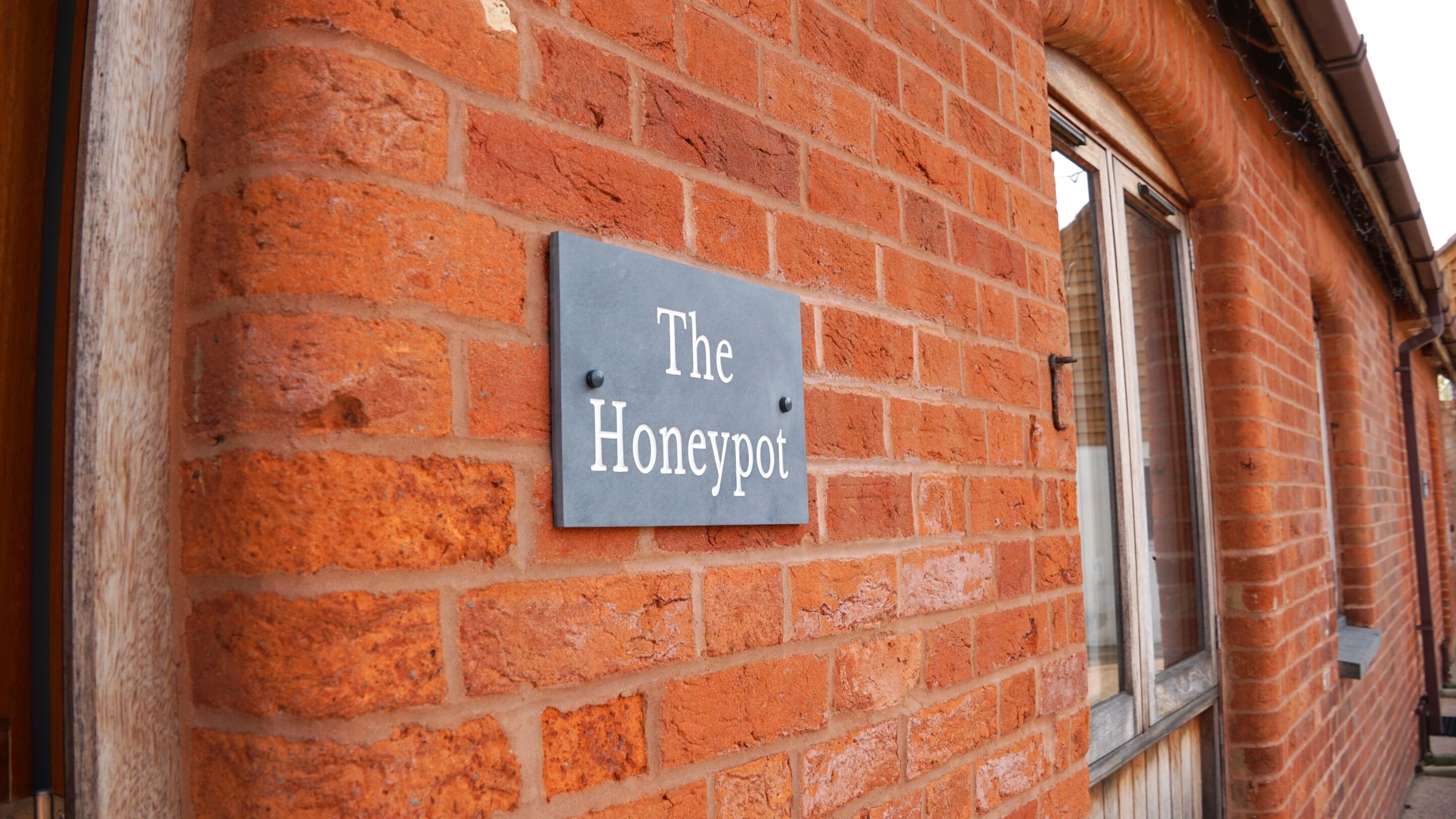 A brick wall with a sign that reads 'The Honeypot.'