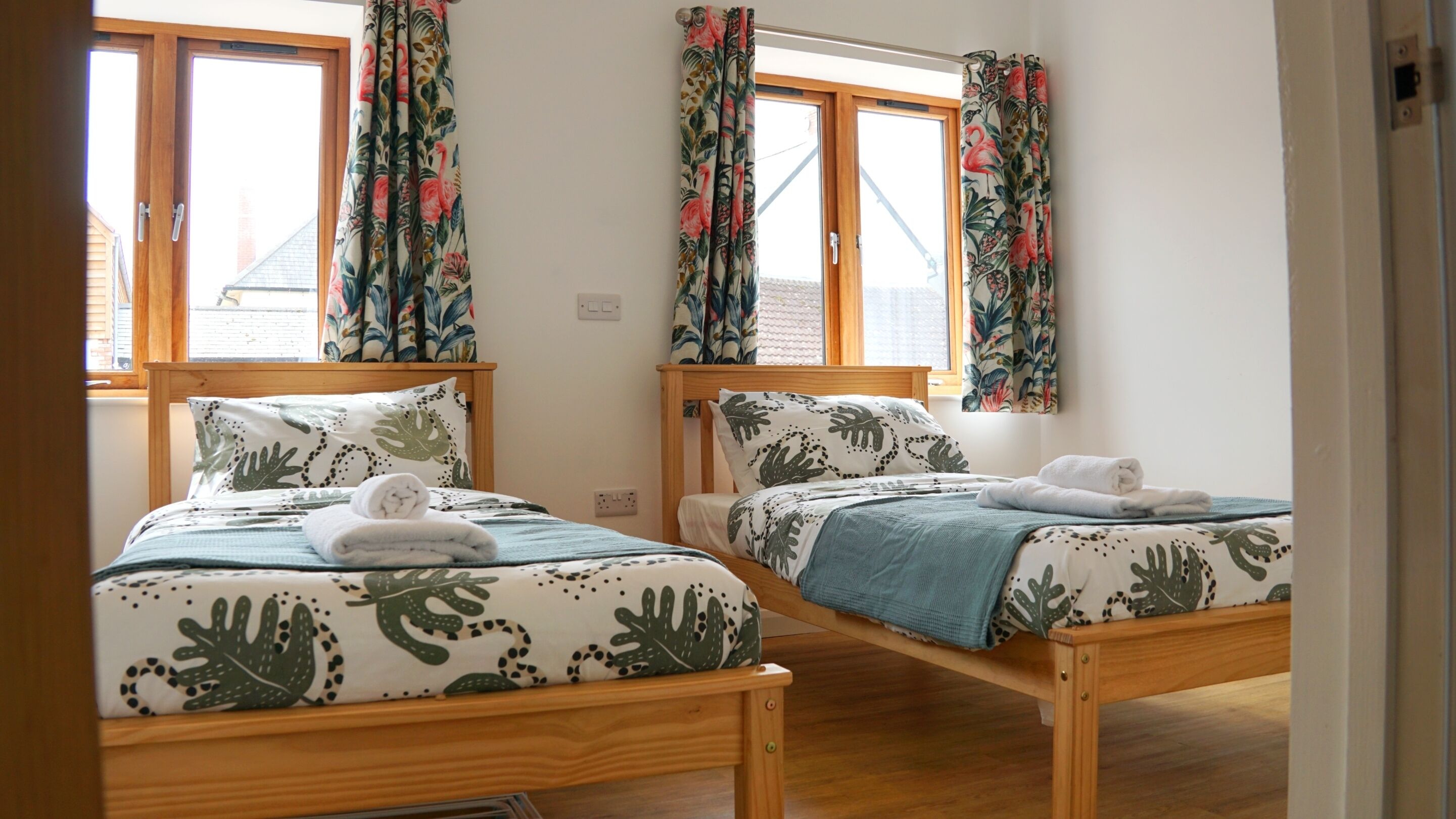 Una habitación con dos camas de madera, cada una con una colcha y almohadas a juego con estampado floral.