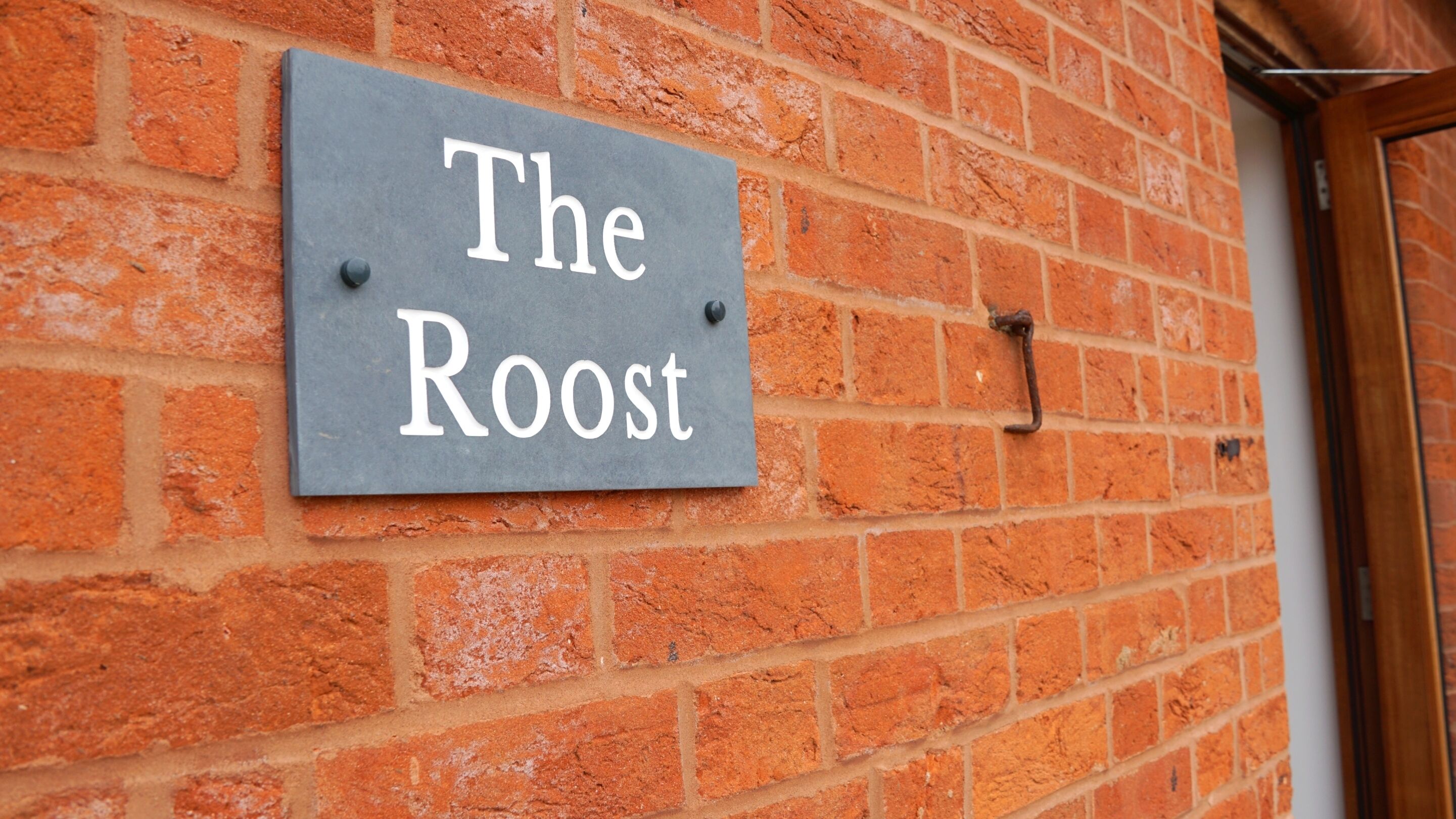 A brick wall with a sign that reads 'The Roost.'