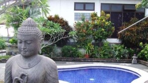 A statue of a seated figure in a courtyard with a pool. - Puri Rasa Villas and Resort (Ubud)