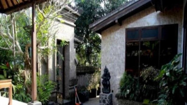 A courtyard with a stone statue, a small pond, and a building with a tiled roof. - Puri Rasa Villas and Resort (Ubud)