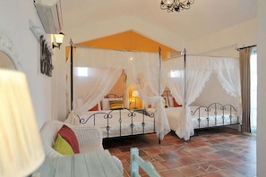 A bedroom with a four-poster bed, a nightstand, and a chair. - Bethlehem B&B & Villa Kenting (Hengchun)