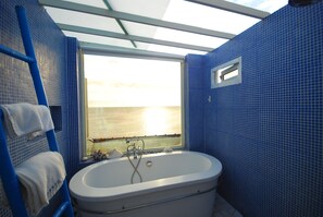 A bathroom with a bathtub, a window with a view of the sea, and blue tiled walls. - Bethlehem B&B & Villa Kenting (Hengchun)