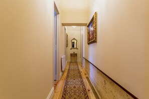 A hallway with a patterned carpet, a mirror, and a framed picture on the wall. - Palácio das Especiarias (Lisbon)