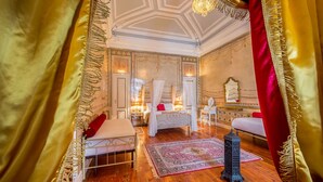 Un dormitorio lujoso con cama con dosel, decoración ornamentada y una araña.