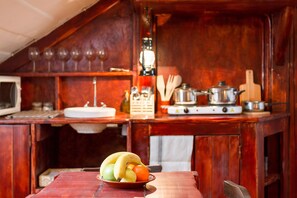 Una cocina rústica con armarios de madera, una estufa y un cuenco de fruta sobre la mesa.