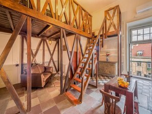 Un espacio tipo loft con escalera de madera, un sofá y una mesa de comedor.