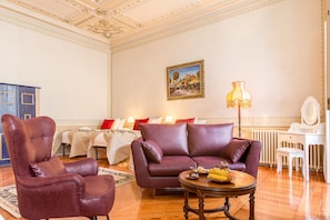 Una habitación con sofá, sillón y una mesa con frutero.