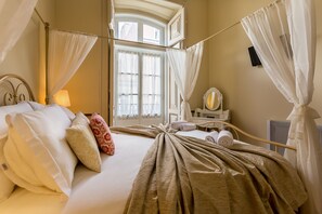 Hotellihuone, jossa on sänky, peilillä varustettu meikkipöytä ja ikkuna, jossa on verhot.