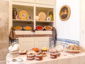 Una mesa de buffet con diversos alimentos y un aparador con frascos y platos.