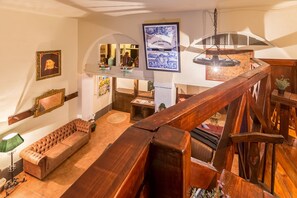 Amplia sala de estar con techo alto, una escalera de madera y vista a un nivel inferior.