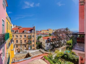 A multi-story building with balconies, a clear sky, and a view of the sea. - Palácio das Especiarias (Lisbon)