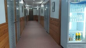 A hotel corridor with wooden paneling, a UNICOOLA refrigerator stocked with beverages, and a carpeted floor. - Kimstay9 (Seoul)